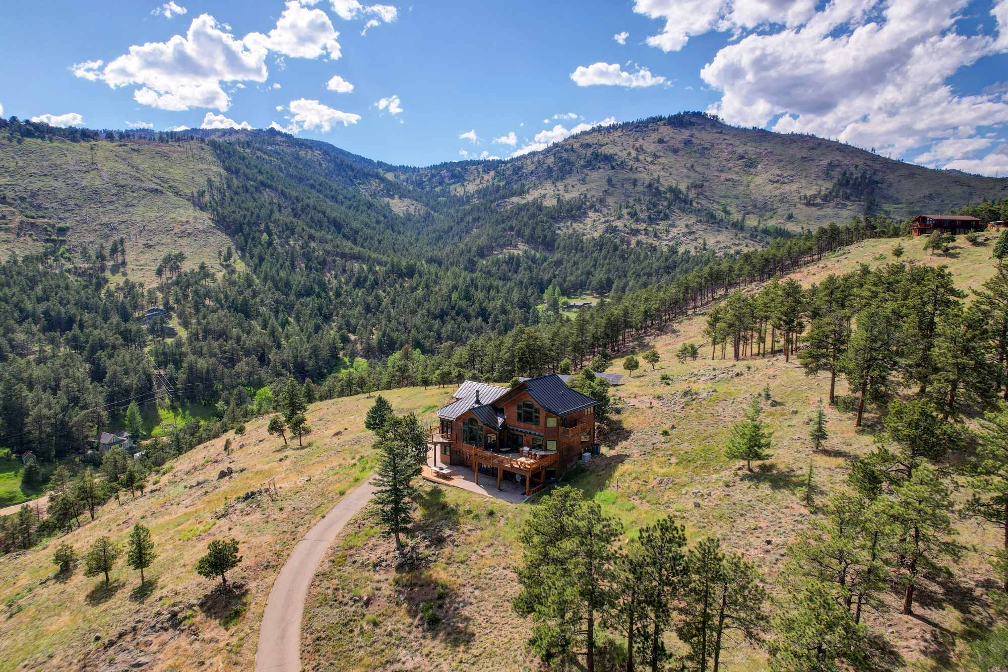 Aerial view of a mountain home on a ridge above a pine valley in the Colorado foothills