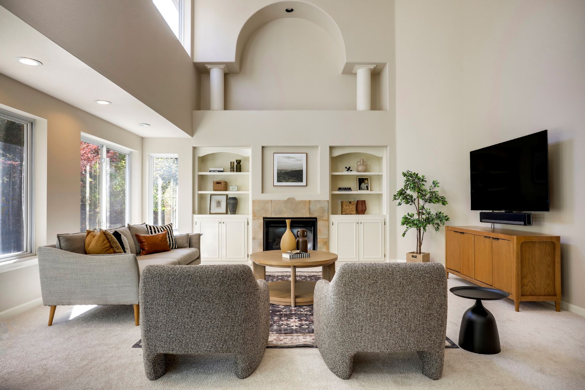 Bright living room with a vaulted arched alcove, built-in shelving, and a fireplace