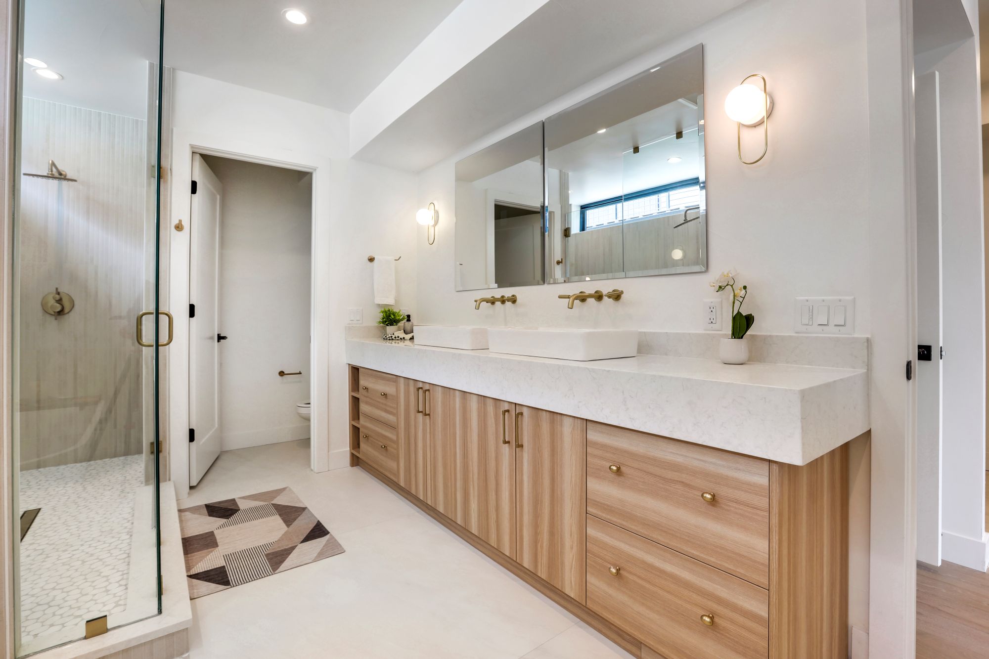 Primary bathroom with a light oak double vanity, vessel sinks, and a glass walk-in shower